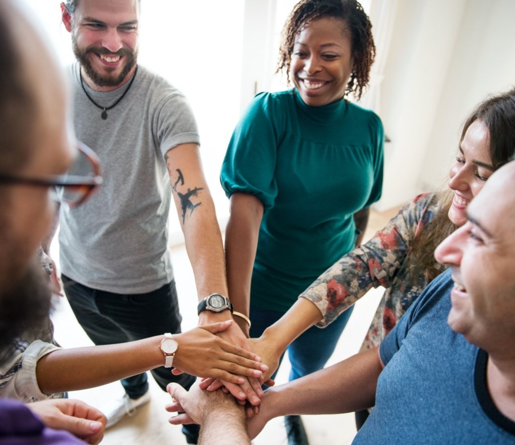 Group of people doing a team cheer at the end of an addiction recovery support group meeting